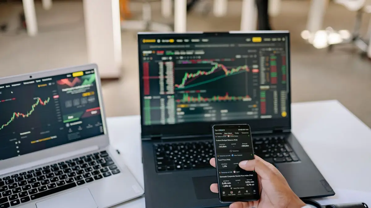 Laptops and a smartphone showing financial charts